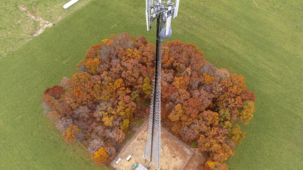 Aerial view of a lattice telecom tower above a base station equipment compound